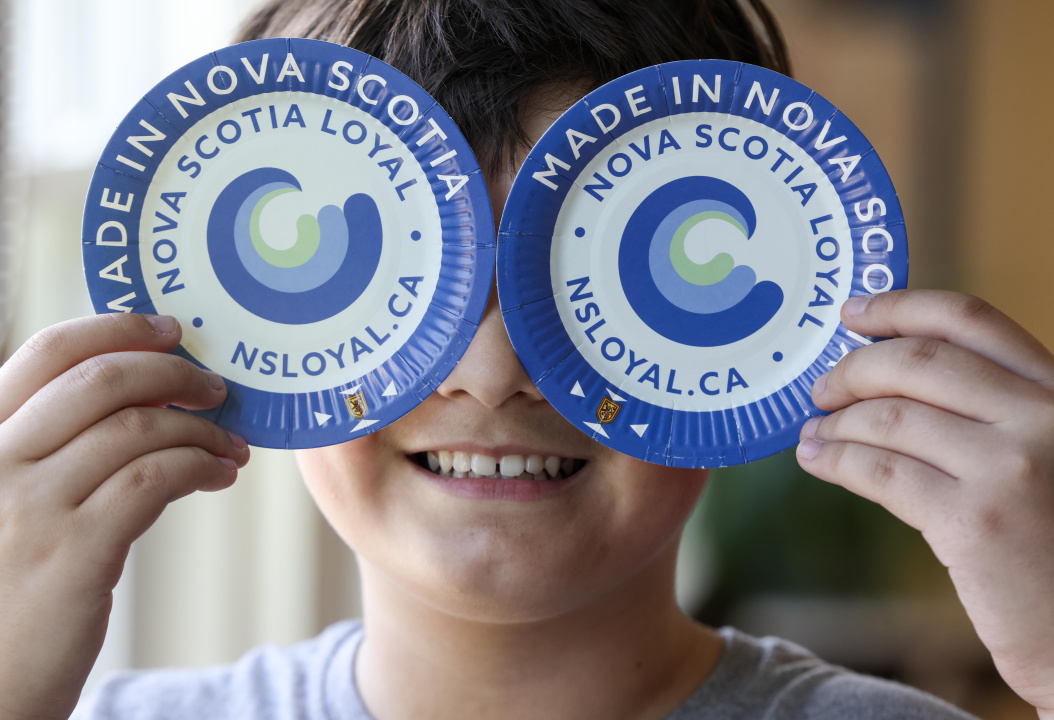 A student holding two Nova Scotia Loyal plates in front of their face. 