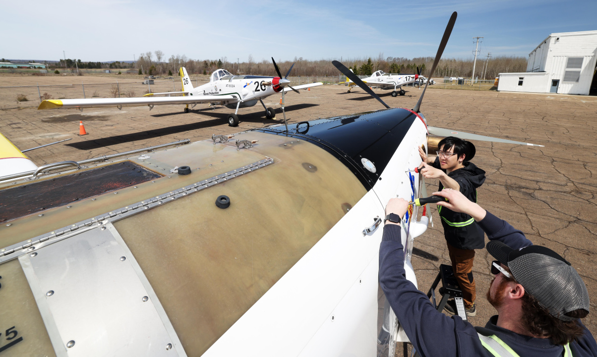 Two engineers work on the cowling covering on an AT-802 water bomber. 