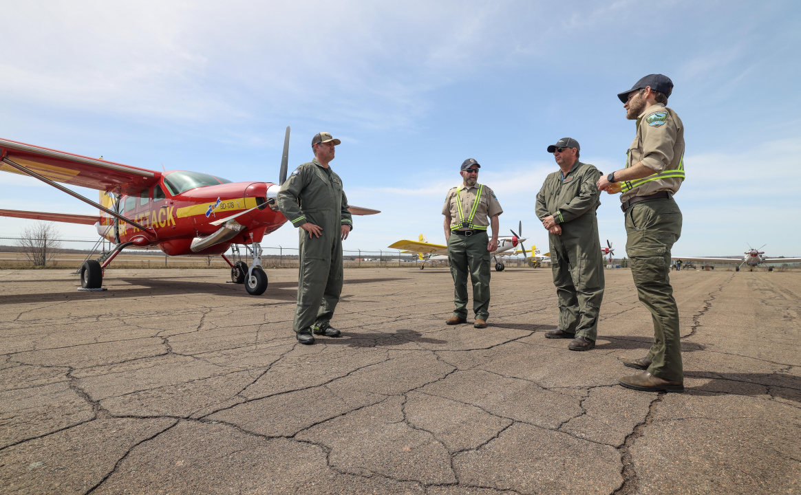 Four crew members in front of the Bird Dog plane.