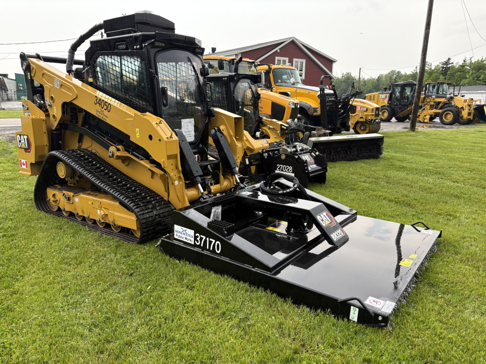 Equipment for road maintenance is parked on a lawn.