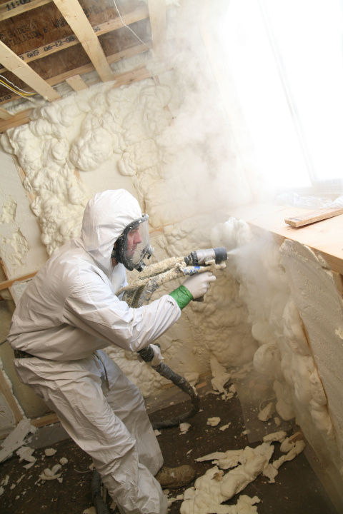 A worker sprays foam insulation in a home. 