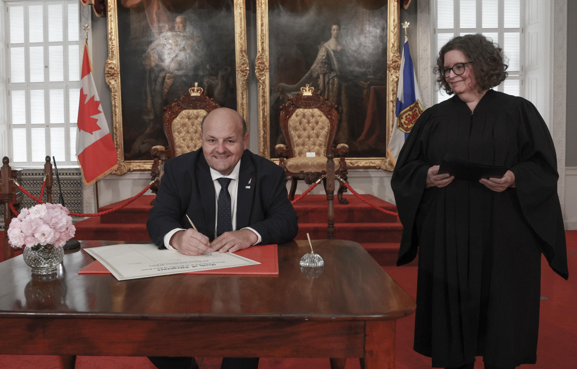 MLA Claude Bourgeois signs the oath of allegiance in the Red Chamber at Province House