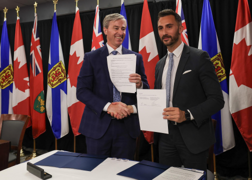 Premier Tim Houston and Ontario Minister Stephen Lecce shake hands while holding copies of an MOU