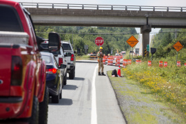 A construction worker holds a stop sign alongside a line of traffic.