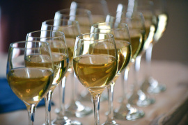 Two rows of wine glasses containing wine.