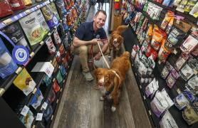 Growth and Development Minister Colton LeBlanc with two Nova Scotia Duck Tolling Retrievers at a specialty pet store