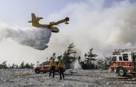 Department of Natural Resources firefighters Dylan Mulder, left, of Jeddore, and ElijaA water bomber make a pass over the wildfire. (Province of Nova Scotia)  ---