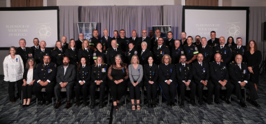 Three rows of paramedics posing for a group photo at an award ceremony