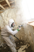 A worker sprays foam insulation in a home. 