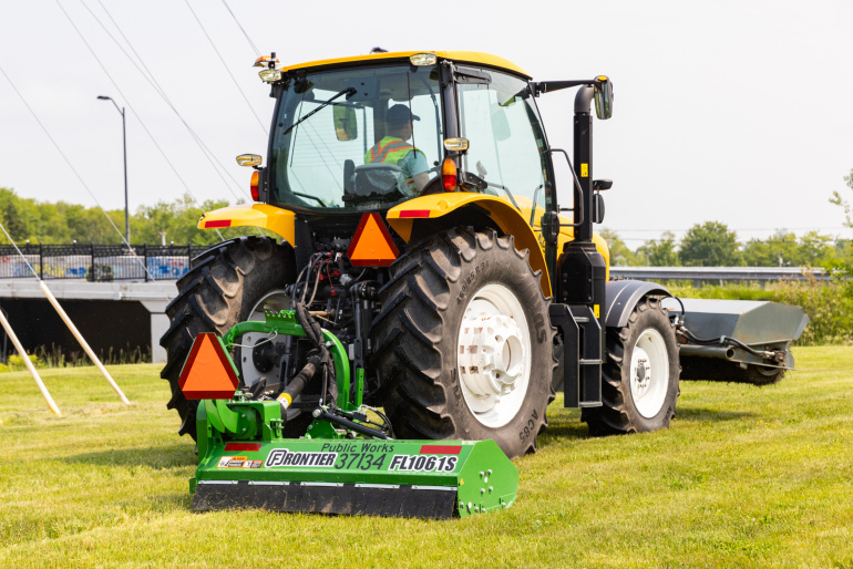 A Public Works tractor pulls a new mower attachment.