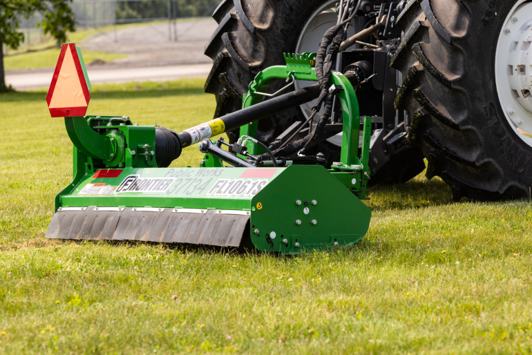 A new mower attachment is pulled behind a tractor.