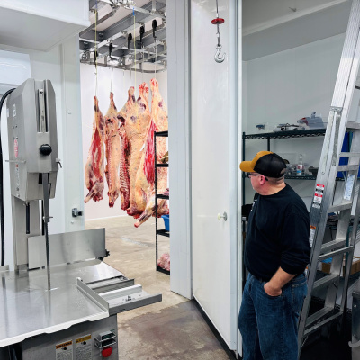 Meat hanging from hooks and a person giving a tour 